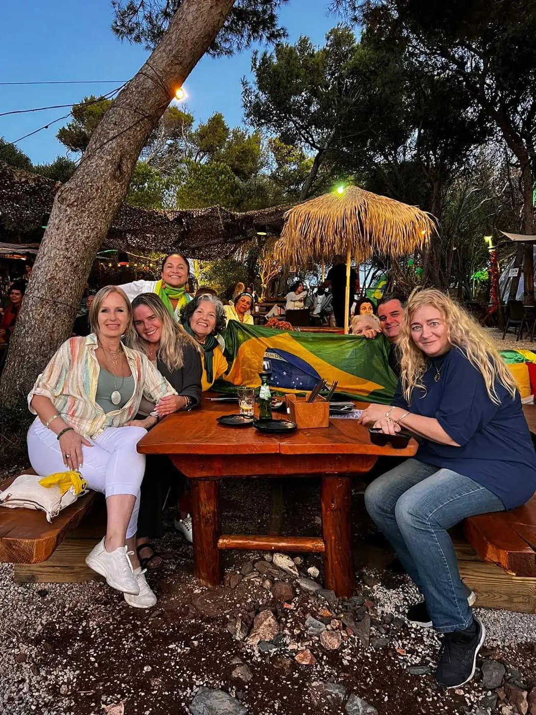 Mesa de convívio à sombra das árvores, com o grupo reunido