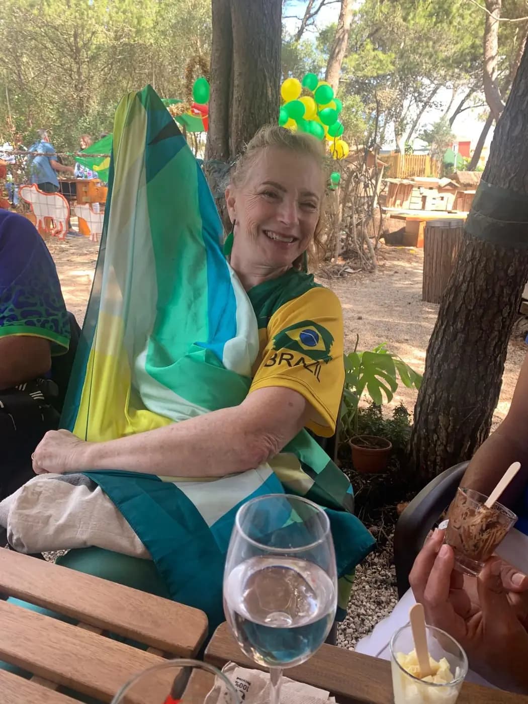 Convidada com a bandeira do Brasil aos ombros, sentada à mesa