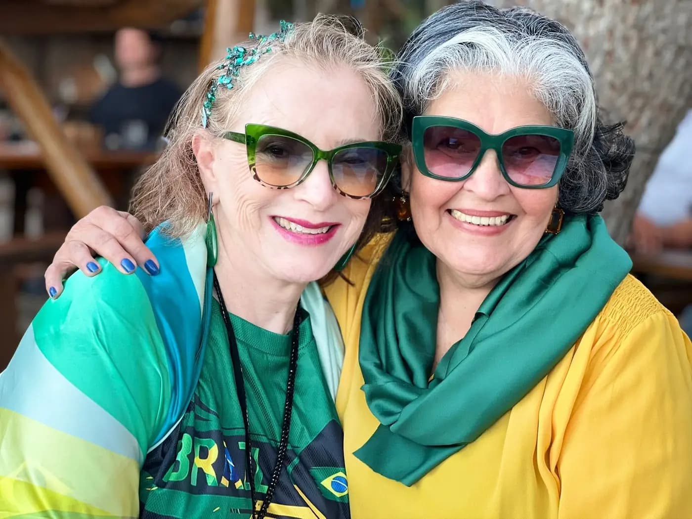Duas associadas em verde e amarelo, de óculos a condizer