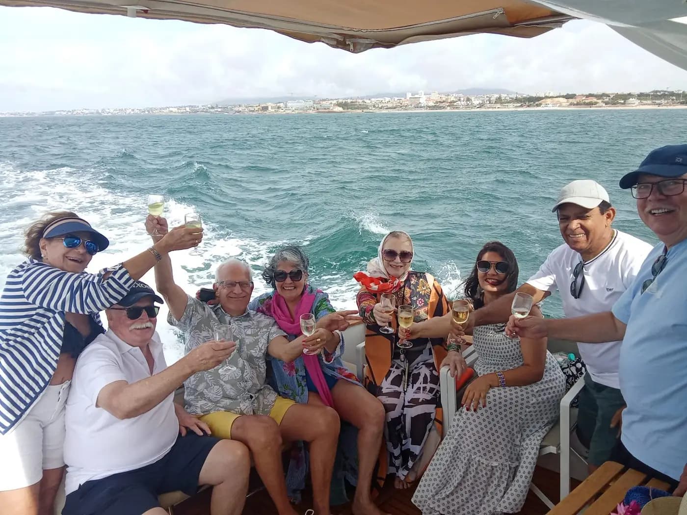 Brinde do grupo no convés, com a linha de costa ao fundo