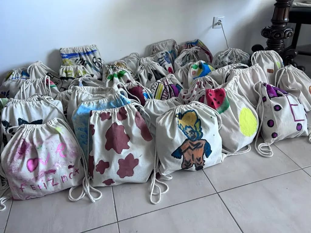 Mochilas de pano pintadas pelas crianças, alinhadas no fim da atividade